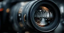 A camera lens brings a blurry government office into sharp focus, symbolizing the IOV's role in scrutinizing the Victorian Ombudsman's failures.
